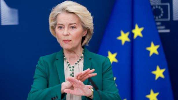Ursula von der Leyen spricht vor der Europaflagge und gestikuliert.