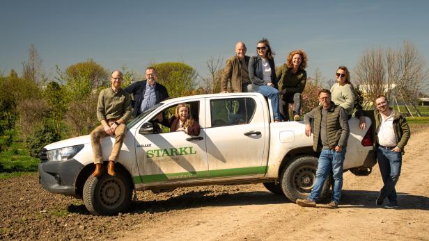 Mehrere Mitglieder der Familie Starkl posieren gemeinsam auf und neben einem Firmenfahrzeug im Grünen anlässlich des 110-jährigen Jubiläums der Gärtnerei.