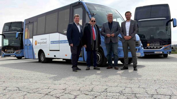 Vier Männer in Anzügen stehen vor drei blauen Bussen mit der Aufschrift „burgenland“ auf einem asphaltierten Platz.