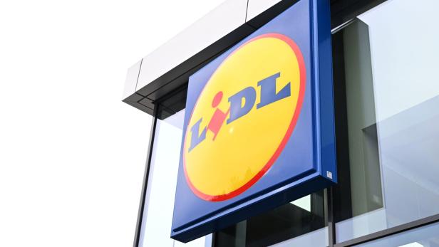 Ein blaues Lidl-Schild mit gelbem Kreis hängt an einer modernen Glasfassade.