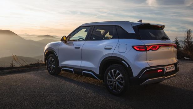 BYD Atto 2 DM-i von links hinten vor Bergkulisse bei Sonnenuntergang.