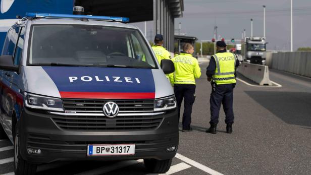 Polizeifahrzeug und mehrere Polizisten bei einer Verkehrskontrolle auf einer Autobahn.
