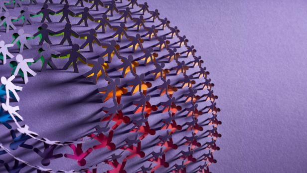 Colorful interconnected paper chain of human figures forming a spiraling design symbolizing unity and diversity.