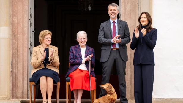 Königin Margrethe, Familie und ein Dackel stehen auf einer Treppe und klatschen.