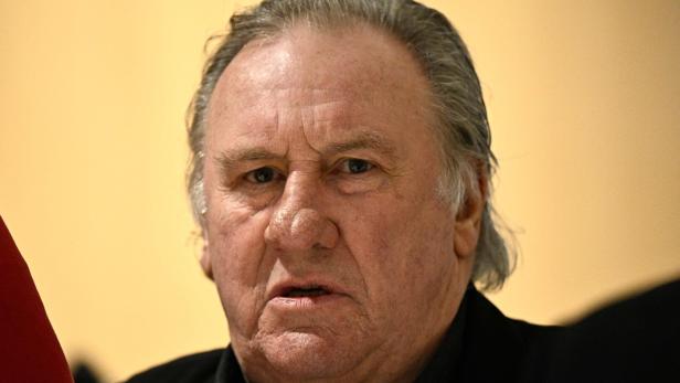 Nahaufnahme von Gérard Depardieu vor einem hellgelben Hintergrund.