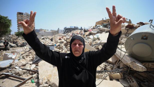 A woman makes a peace sign at the site of an Israeli strike carried out before a 10-day ceasefire between Lebanon and Israel went into effect, in Tyre