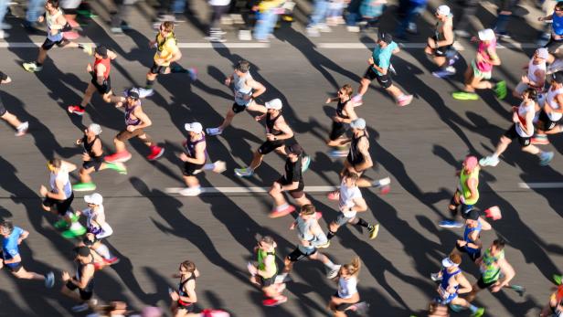 Eine Menschenmenge rennt einen Marathon auf einer asphaltierten Straße entlang.