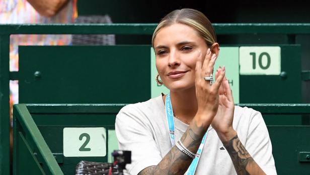 Sophia Thomalla mit Tattoos klatscht auf der Tribüne mit grünen Sitzen.