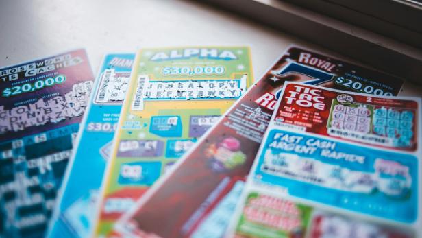 Mehrere bunte Rubbellose liegen nebeneinander auf einer Fensterbank.