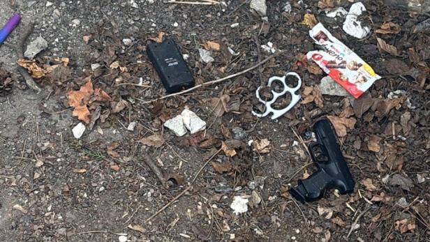 Waffen liegen auf erdigem Untergrund.