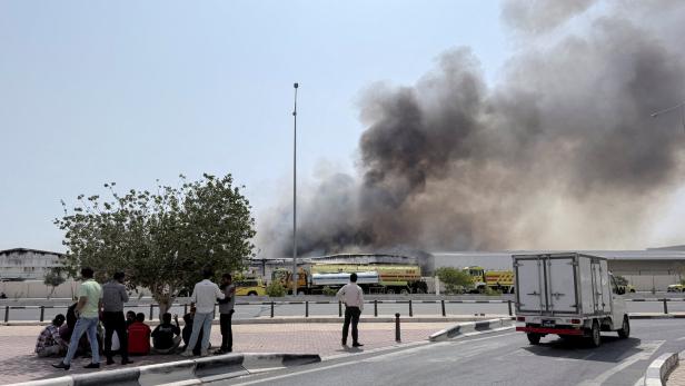 FILE PHOTO: People gather as smoke rises at the Industrial Area after reported Iranian missile attacks, following United States and Israel strikes on Iran, in Doha