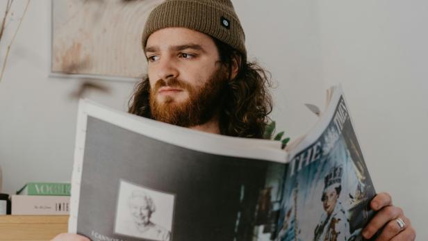 Ein junger Erwachsener liest eine gedruckte Zeitung.