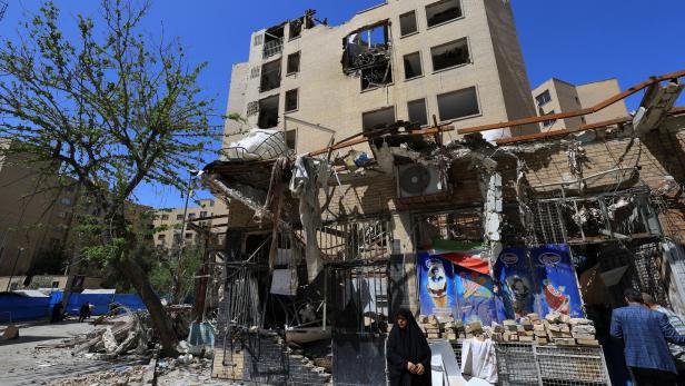 A woman stands next to debris lying in front of a residential building damaged by a strike on March 4, in Tehran