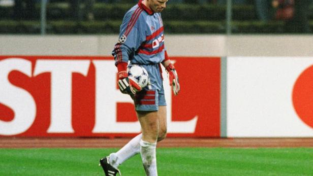 Ein Fußballspieler mit Ball in der Hand geht über den Rasen.