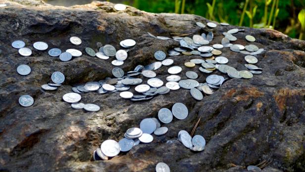 Münzen auf Steinen im Garten platziert.