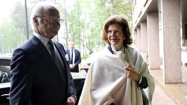 König Carl Gustaf und Königin Silvia von Schweden stehen draußen vor einem Gebäude.