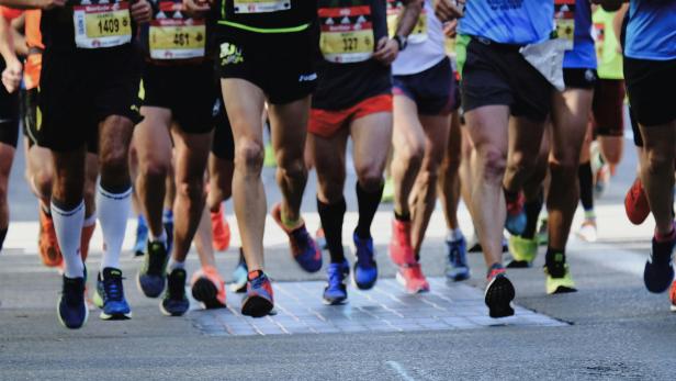 Läufergruppe in Sportsachen läuft gemeinsam auf einer Straße während eines Marathons.