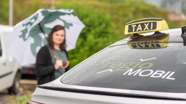 Eine Frau steigt in das Regio Mobil bei Regen ein