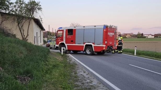 Feuerwehrauto und Einsatzkräfte sperren eine Landstraße bei Sonnenuntergang.