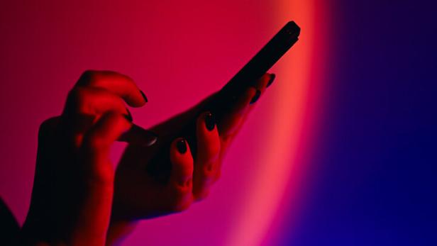 Person holding smartphone on vibrant neon background
