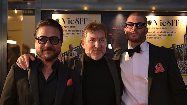 Drei Männer in Anzügen stehen nebeneinander