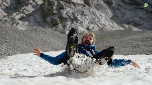 Ein Mann stürzt im Schnee vor einem felsigen Berghang und schreit.