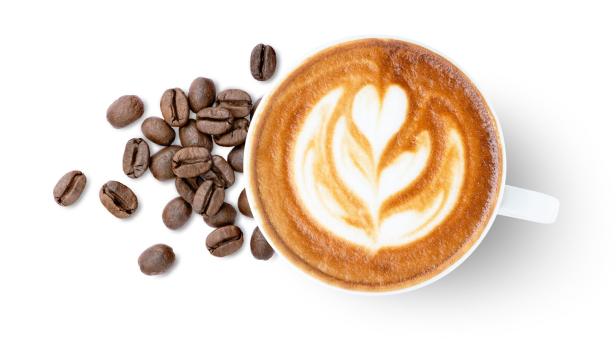 Das Bild zeigt eine Tasse Cappuccino, daneben liegen Kaffeebohnen.