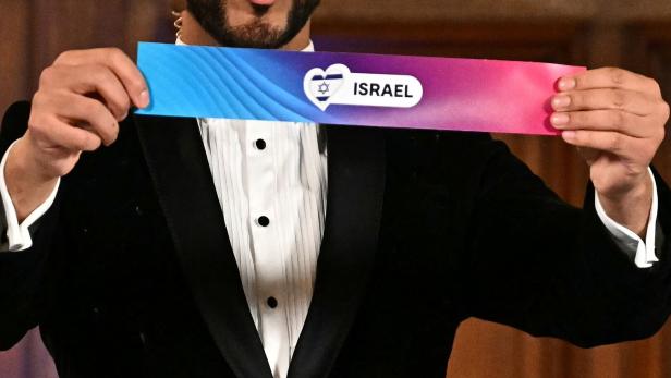 Eurovision Song Contest Ein Mann im Smoking hält einen Zettel mit der Aufschrift „Israel“ und einem Herzsymbol mit Davidstern.