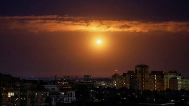 Eine leuchtende Explosion am Nachthimmel über einer Stadt mit beleuchteten Hochhäusern.