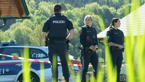 Drei Polizisten stehen vor einem Polizeiauto mit der Aufschrift "Polizei".