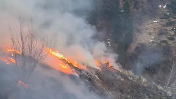 Flammen und dichter Rauch breiten sich auf einer bewaldeten Hangfläche bei Sölden im Ötztal aus.