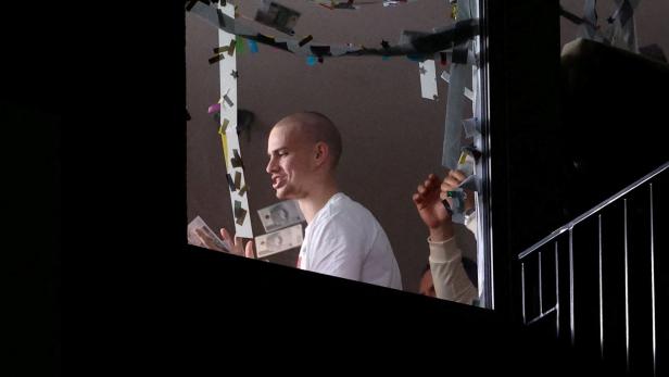 Youtuber Latwogang mit Geldscheinen steht unter einer Girlande mit Papierstücken.