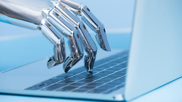 Roboterhand tippt auf einer Laptop-Tastatur.