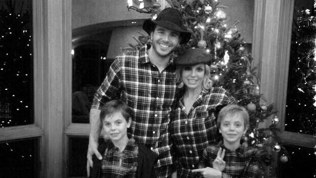 Eine Familie in karierten Pyjamas posiert vor einem Weihnachtsbaum.