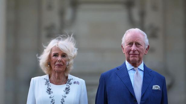 König Charles und Königin Camilla posieren vor einem Gebäude.
