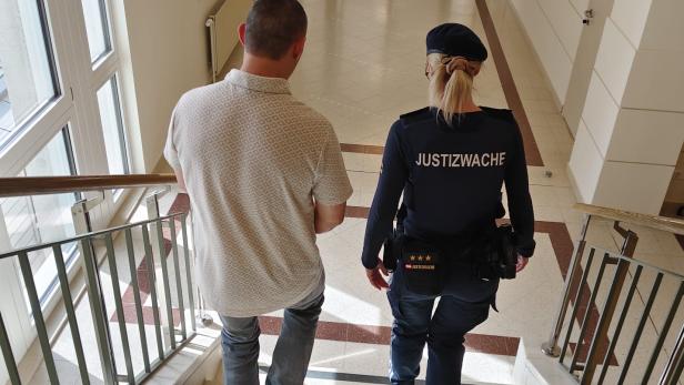 Angeklagter und Justizwachebeamte gehen Stiegen hinunter.