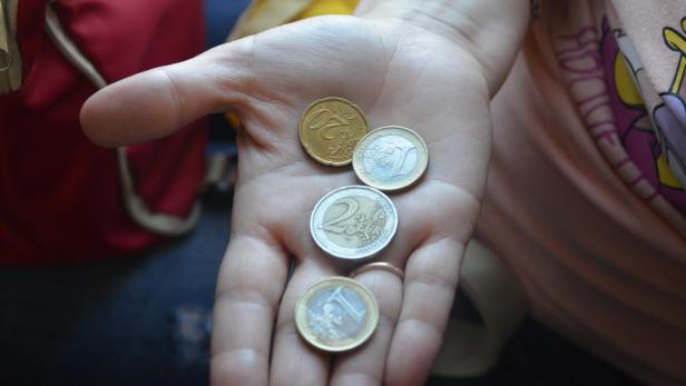 Eine Hand auf der sich ein paar Euro-Münzen befinden
