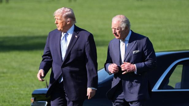 Donald Trump und König Charles III. gehen vor einem schwarzen Auto.