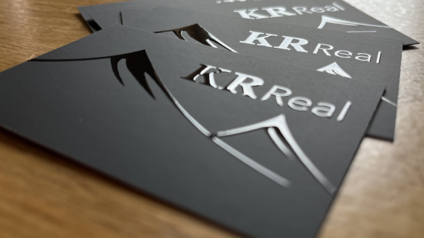 Visitenkarten mit dem Logo von K R Real, professionell gestaltet.