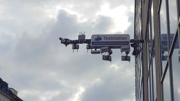 Mehrere Überwachungskameras und Scheinwerfer an einem Gebäude mit Schild „Teststation“.