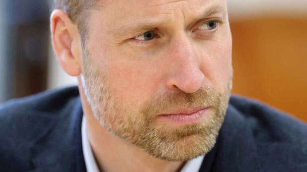 Prinz William mit Bart und dunklem Sakko blickt aufmerksam zur Seite.