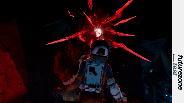 Eine Person im Raumanzug steht vor einer leuchtenden, roten, außerirdisch wirkenden Struktur mit spitzen Auswüchsen.