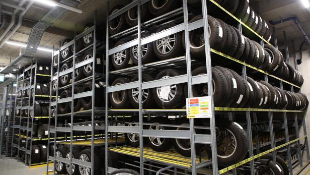 Mehrere Reihen Autoreifen mit Felgen sind ordentlich in einem Lagerregal gestapelt.