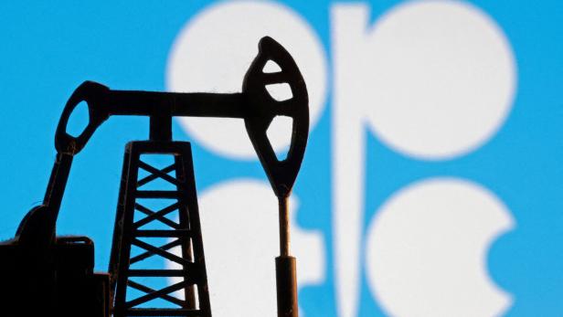 Eine Ölförderanlage steht vor dem OPEC-Logo auf blauem Hintergrund.