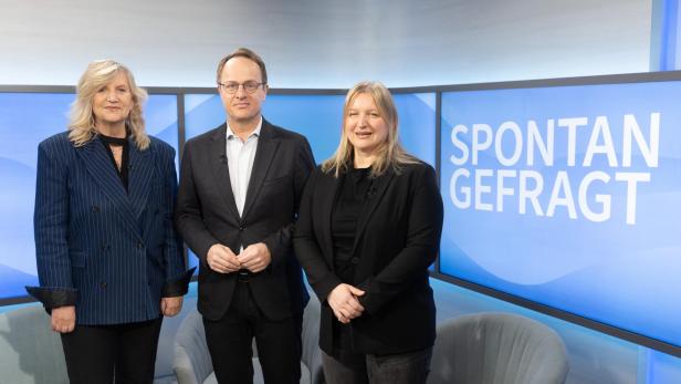 Drei Personen stehen vor einem Bildschirm mit der Aufschrift 'SPONTAN GEFRAGT' in einem Fernsehstudio
