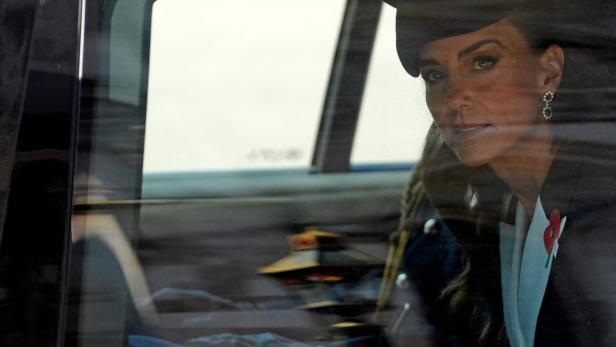 Prinzessin Kate, mit Hut und Mohnblume, blickt aus dem Autofenster.