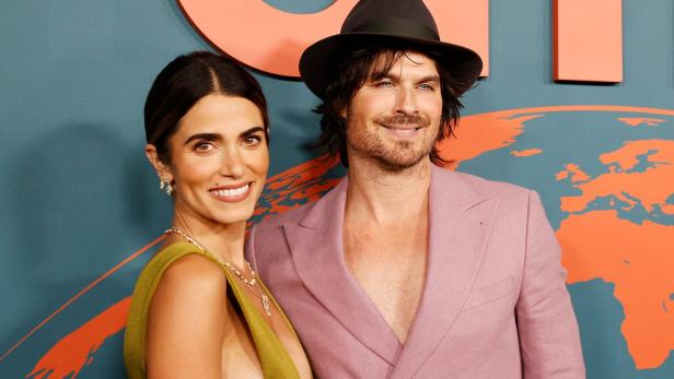 Schauspieler Ian Somerhalder mit Hut und seine Frau Nikki Reed lächeln vor einem farbigen Hintergrund.