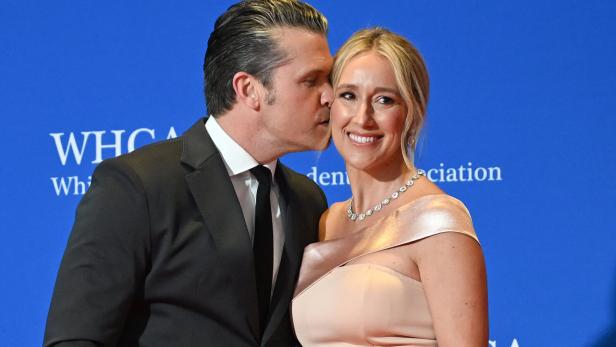 Ein Mann im Anzug gibt einer Frau im Abendkleid einen Kuss auf die Wange.