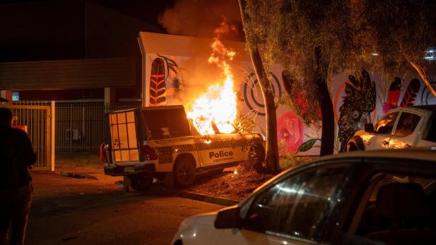 A police vehicle burns after community members clashed with police outside Alice Springs Hospital, where a 47-year-old man arrested in connection with the alleged killing of five-year-old Kumanjayi Little Baby was taken, in Alice Springs
