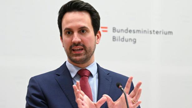Ein Mann im Anzug spricht vor dem Hintergrund des Bundesministeriums für Bildung.